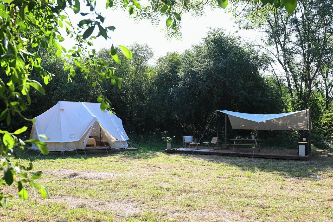 A tented camping area with a picnic table and seating.