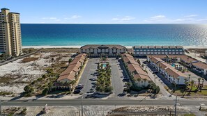 A coastal hotel with a parking lot, beachfront view, and a large building with multiple balconies. - Sugar Beach F-28 ~ Gulf-side luxury townhome! (Navarre)