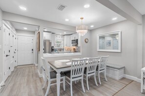 Une cuisine moderne avec des meubles blancs, une table à manger avec des chaises et un lustre.