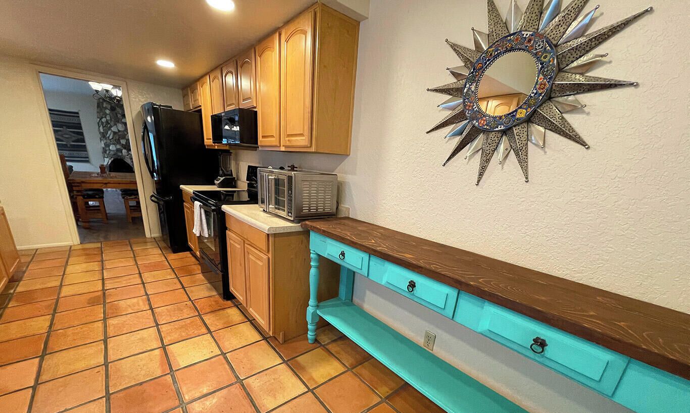 Una cocina con armarios de madera, microondas, refrigerador y un adorno en la pared.