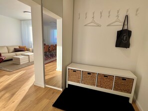 Ein modernes Wohnzimmer mit Sofa, Couchtisch und einem Essbereich im Hintergrund sowie einem Flur, der in ein weiteres Zimmer führt.