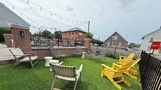 Eine Terrasse im Freien mit Kunstgrasanlage, Gartenmöbeln und Lichterketten.