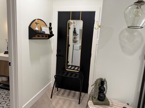 A hallway with a black-framed mirror, a black chair, and a small table with a vase.