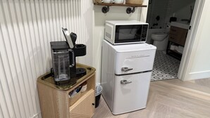 Eine kompakte Küchenzeile mit Kaffeemaschine, Mikrowelle und kleinem Kühlschrank.
