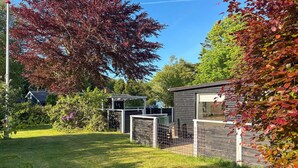 A fenced garden area with a small wooden structure, a metal gate, and a tree with red leaves. - 2 bedroom lovely home in Thyholm (Thyholm)