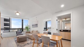 Eine moderne Wohnung mit Essbereich, Küche und großen Fenstern mit Blick auf die Stadt.