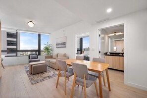 Eine moderne Wohnung mit Essbereich, Küche und großen Fenstern mit Blick auf die Stadt.