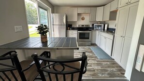 A modern kitchen with a dining area, a built-in oven, and a large window. - 9 cottages on the beach of Lake Huron! (Oscoda)