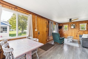 L’intérieur d’une cabine comprenant une table à manger, des chaises, un canapé, un téléviseur et un ventilateur de plafond.