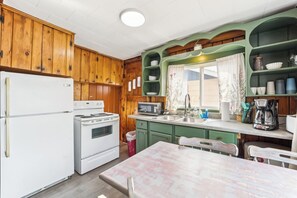 A kitchen with wooden cabinets, a refrigerator, stove, microwave, sink, and a dining table with chairs.