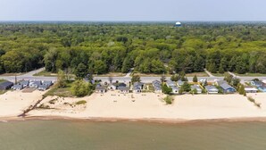 An aerial view of a coastal residential area with houses, a beach, and a water tower in the distance. - #2 | Cozy & Easy - Steps to the Sand (Oscoda)