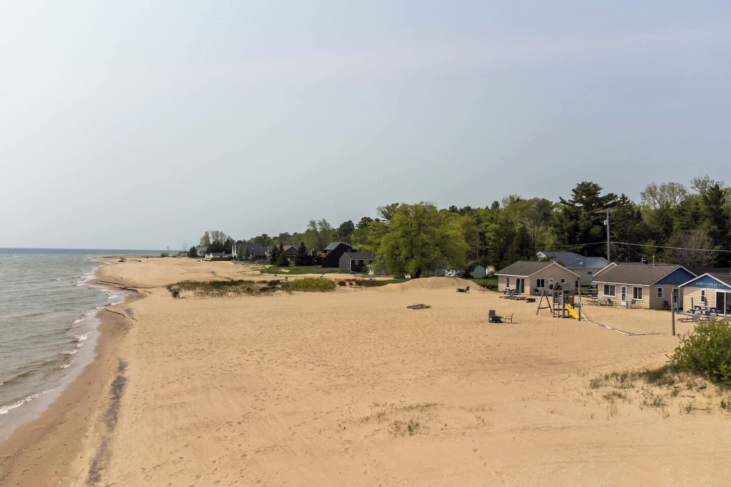 A beach with houses, a playground, and a clear sky.
