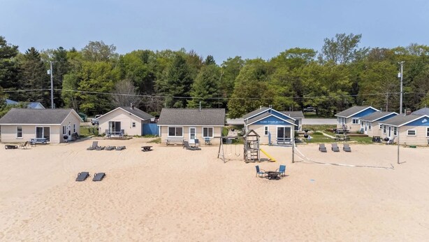 A beachside motel with multiple rooms, a playground, and beach chairs.