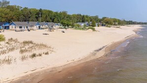 A beachside property with multiple houses, a sandy beach, and a clear view of the ocean.