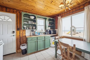 A kitchen with green cabinets, a sink, and a window overlooking a beach. - #5 | Lake Views with Big Windows & New Bath (Oscoda)