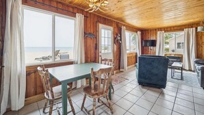 A wooden cabin with a dining table, chairs, a sofa, and a TV.