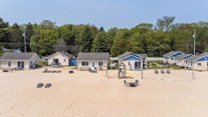 Un motel frente a la playa con varias habitaciones, un parque infantil y sillas para la playa.