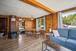A cabin interior with a dining area, a sofa, and a view of the outdoors. - #8 | Spacious & Quiet Near the Sand (Oscoda)