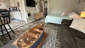 A compact living space with a kitchenette, a dining area, a sofa, and a bed.