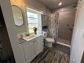 Une salle de bain équipée d’une douche, de toilettes, d’un lavabo et d’un miroir.