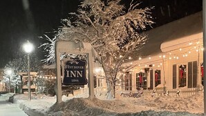 Een met sneeuw bedekte straat met een West Dover Inn bord, een sneeuwduin en een gebouw met verlichting.