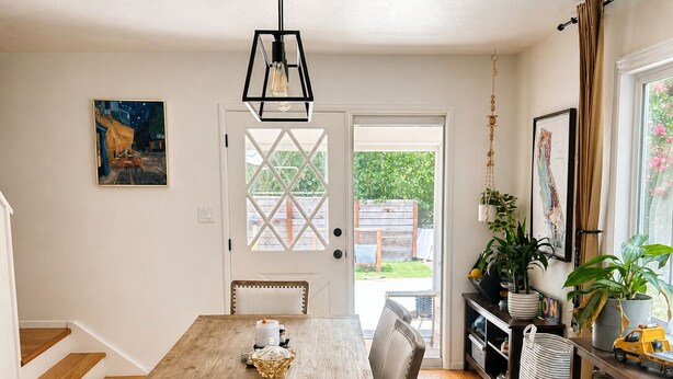 A dining area with a wooden table and chairs, a hanging light fixture, and a view through a door to the outside. - Spacious 4-bedroom house with AC in tranquil Orinda (Orinda)