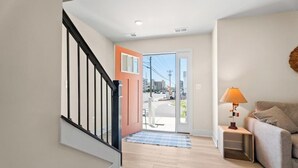 Un couloir avec un escalier, une porte donnant sur l’extérieur, une lampe et un canapé.