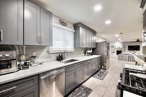 A modern kitchen with stainless steel appliances, grey cabinetry, and a built-in oven. - IAH to Downtown Hideaway -Pool table, Patio &Grill (Houston)