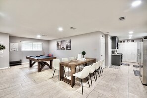 A spacious room with a pool table, dining table with chairs, and a kitchen area. - IAH to Downtown Hideaway -Pool table, Patio &Grill (Houston)