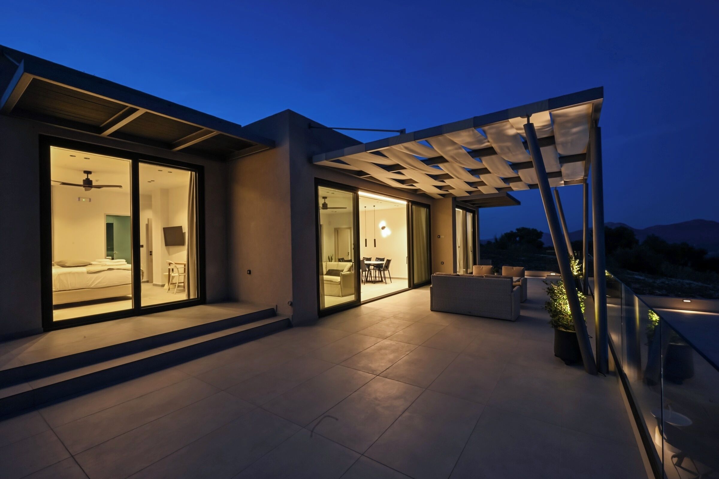 Una casa moderna con patio, amplios ventanales correderas y un ventilador de techo.