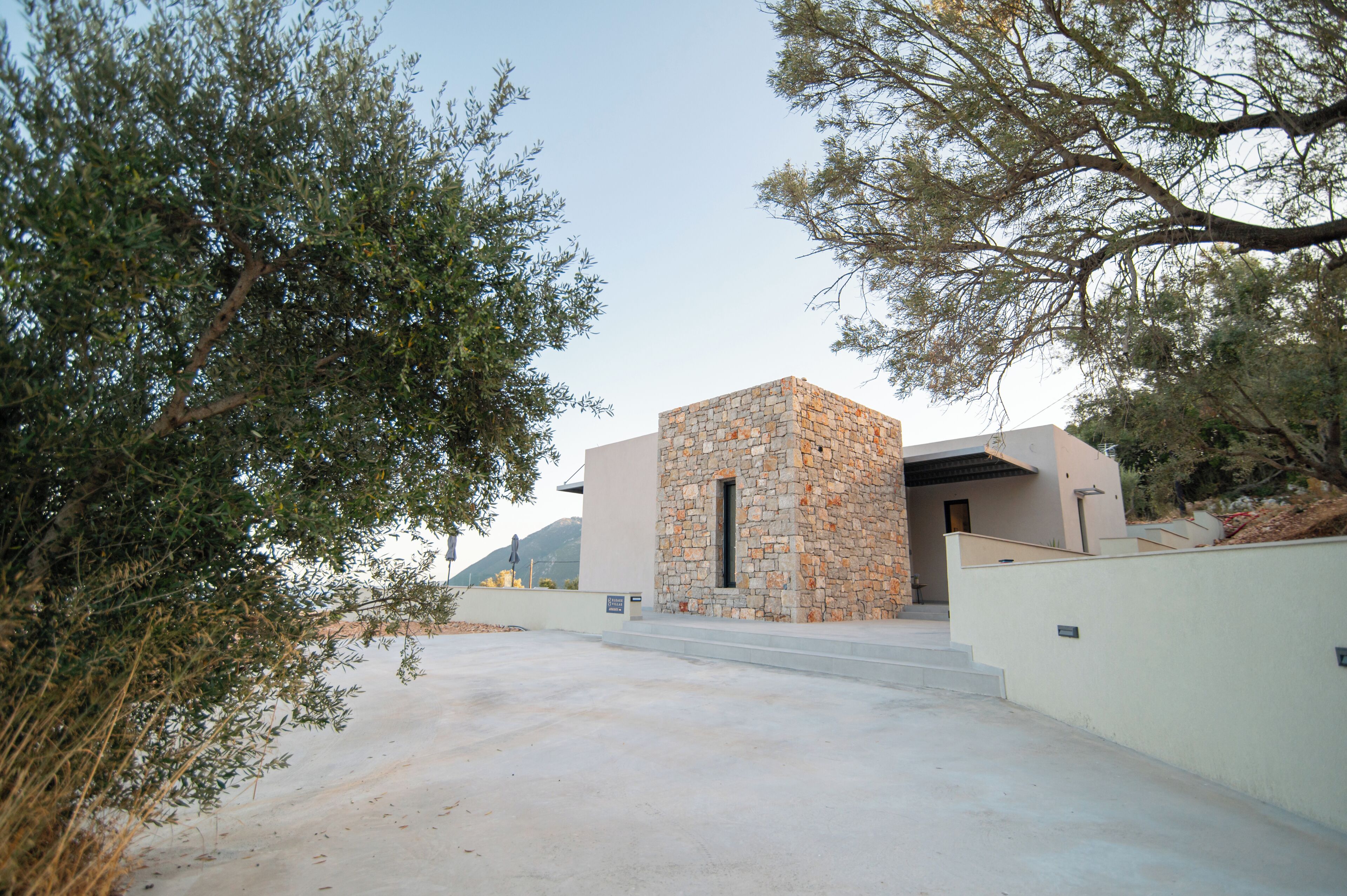 A modern building with a stone facade, a flat roof, and a paved entrance area.
