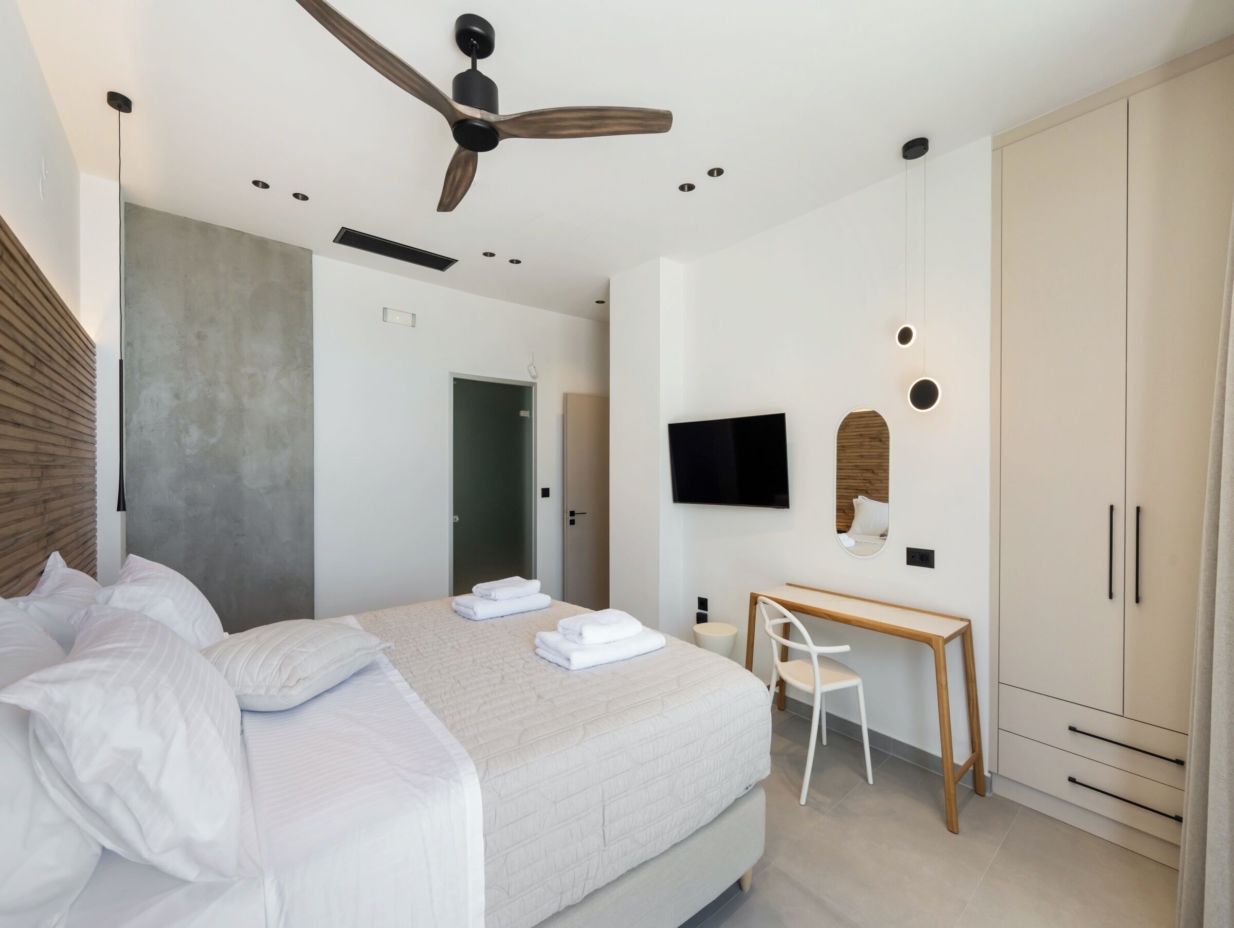 Una camera d'albergo moderna con un letto, una scrivania, una TV e un armadio.