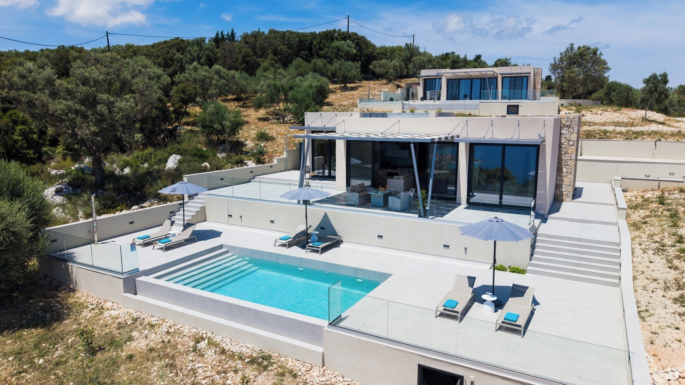 Una villa moderna con piscina, zona de estar exterior y vistas del paisaje circundante.
