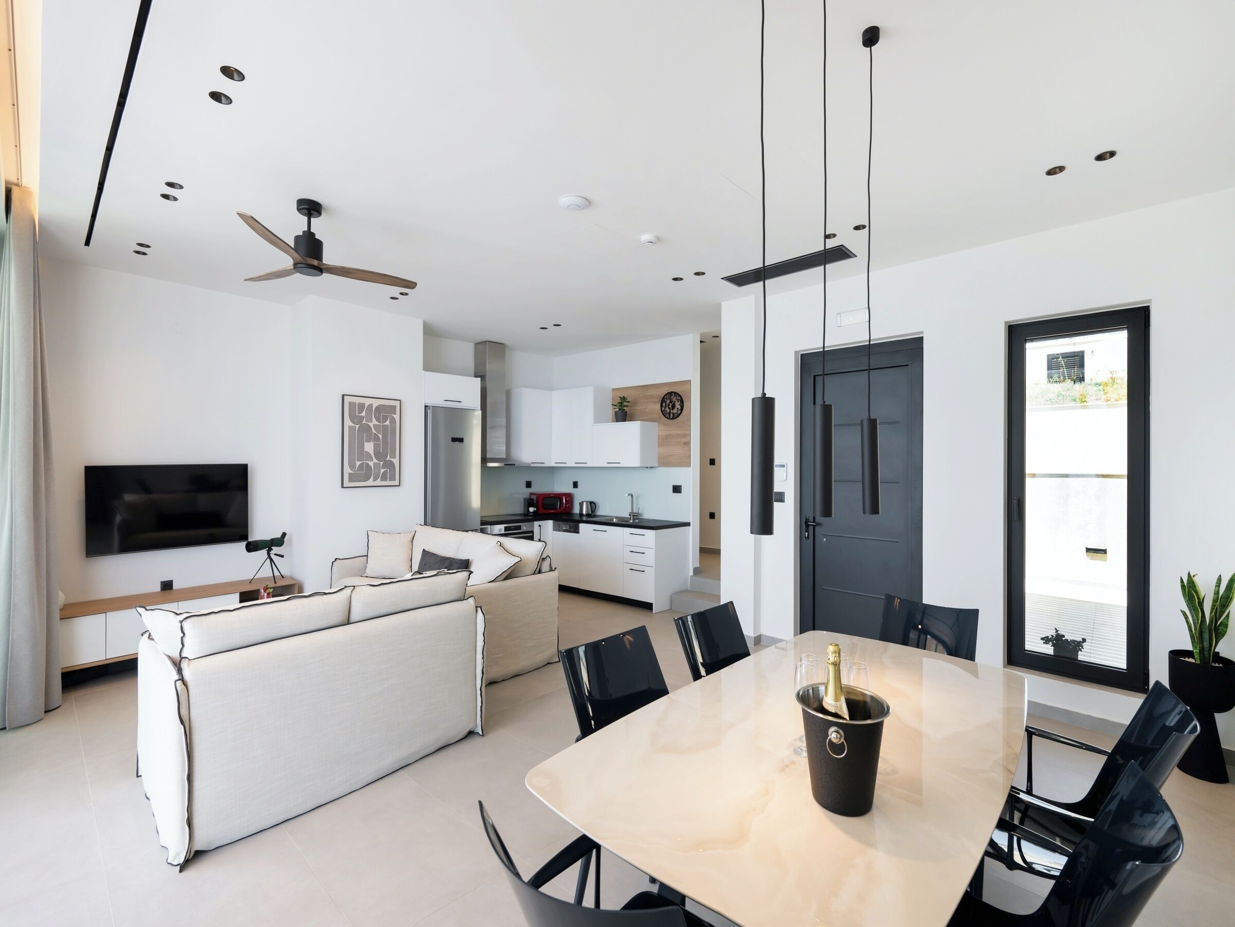 Un espacio habitable moderno con comedor, cocina y televisor de pantalla plana.