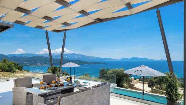 An outdoor seating area with a view of the sea and mountains.