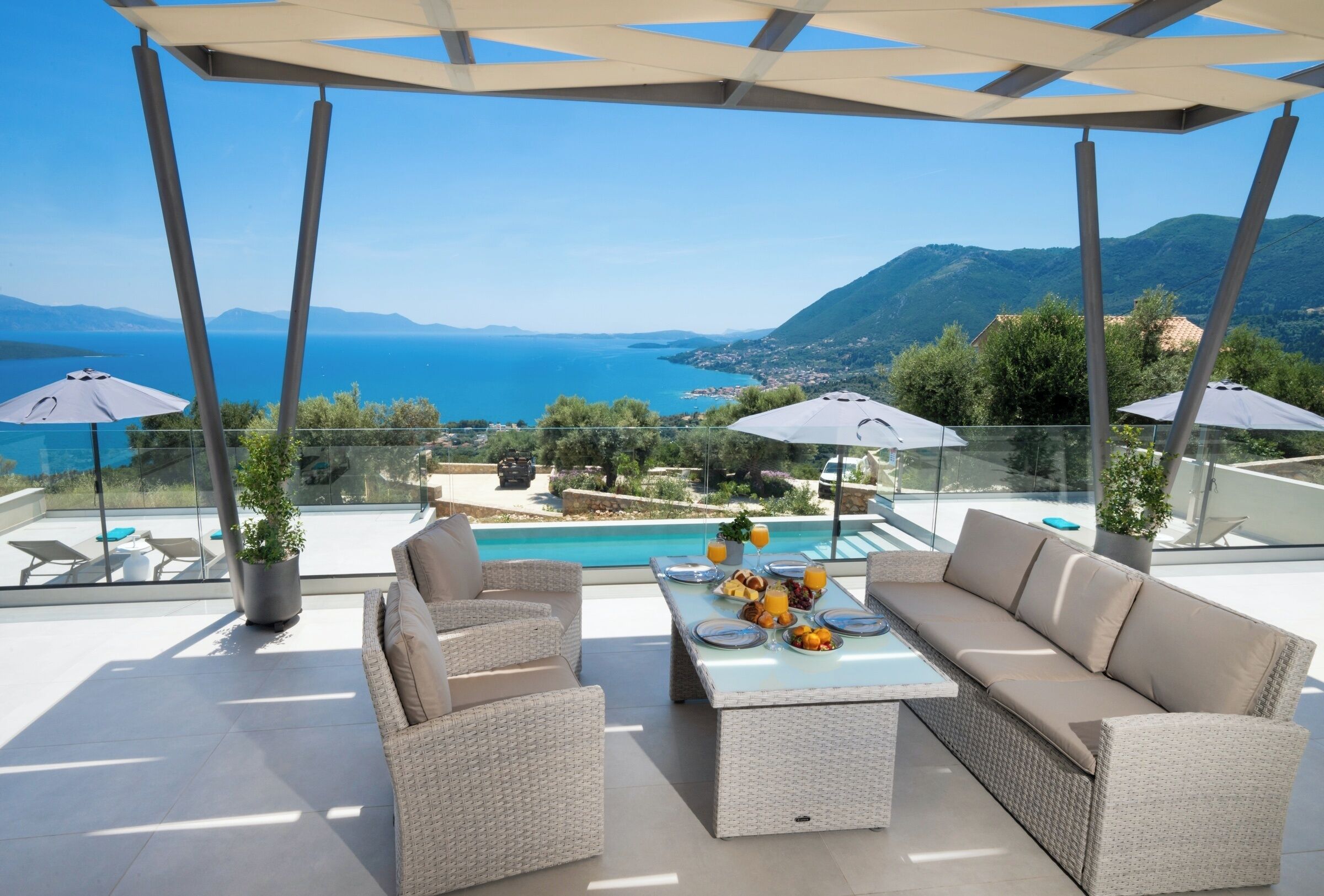 A terrace with a view of the sea, a pool, and outdoor furniture.