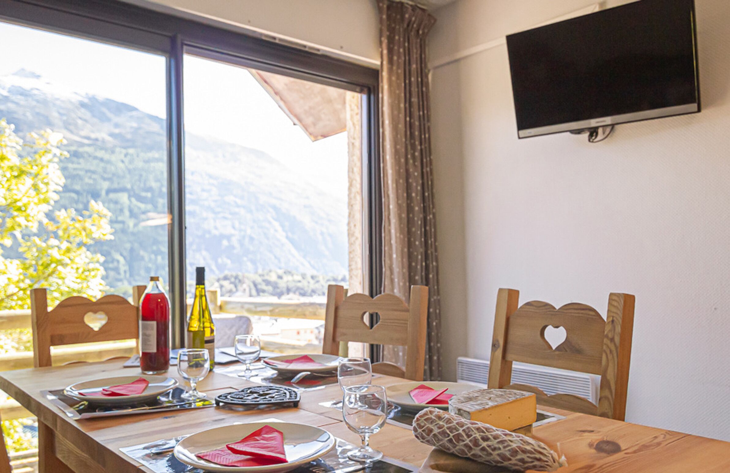 A dining table set with plates, glasses, and cutlery, a bottle of wine, and a cheese board.