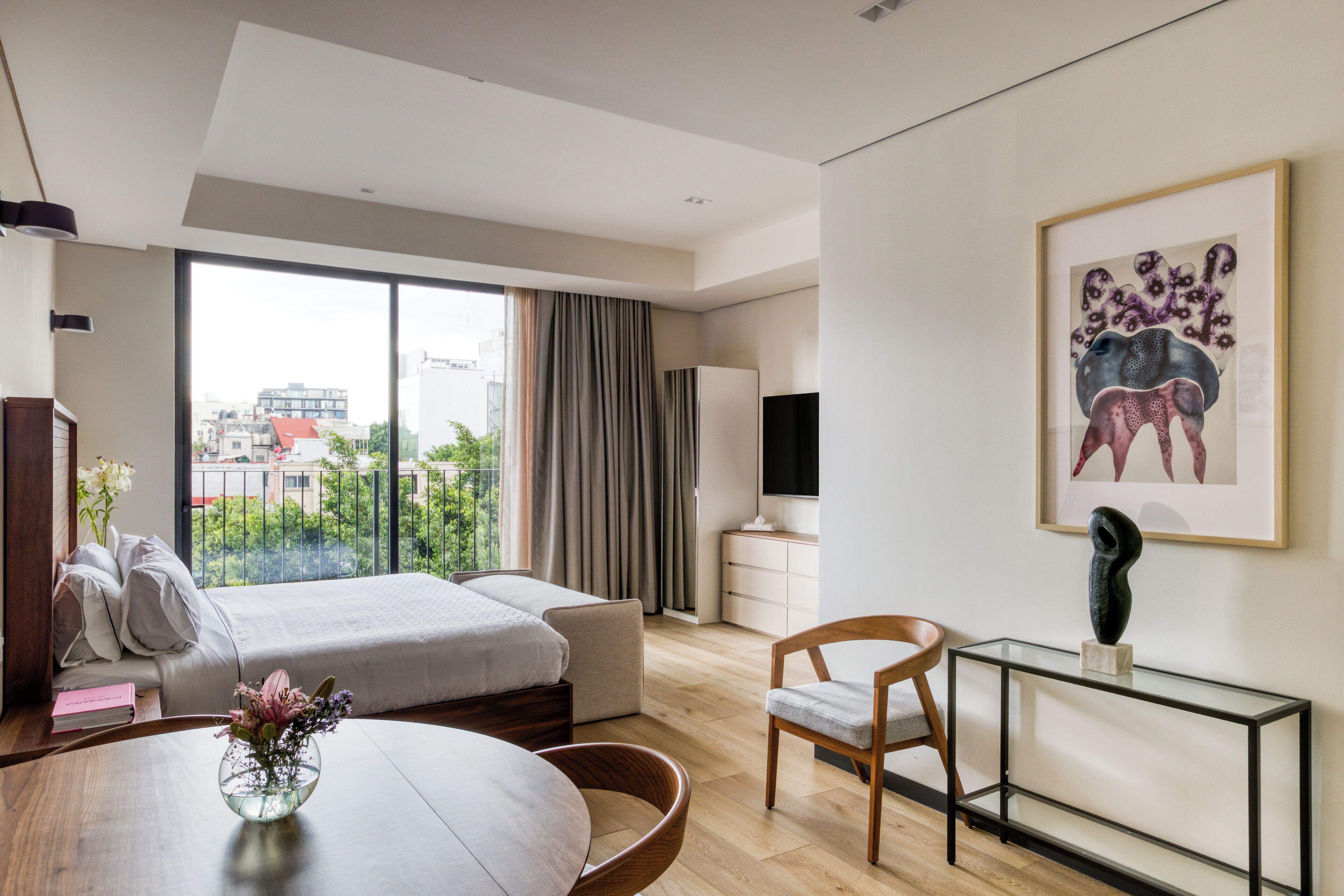 Une chambre d’hôtel moderne dotée d’un grand lit, d’un bureau, d’une chaise, d’une table à manger et offrant une vue sur la ville par la fenêtre.