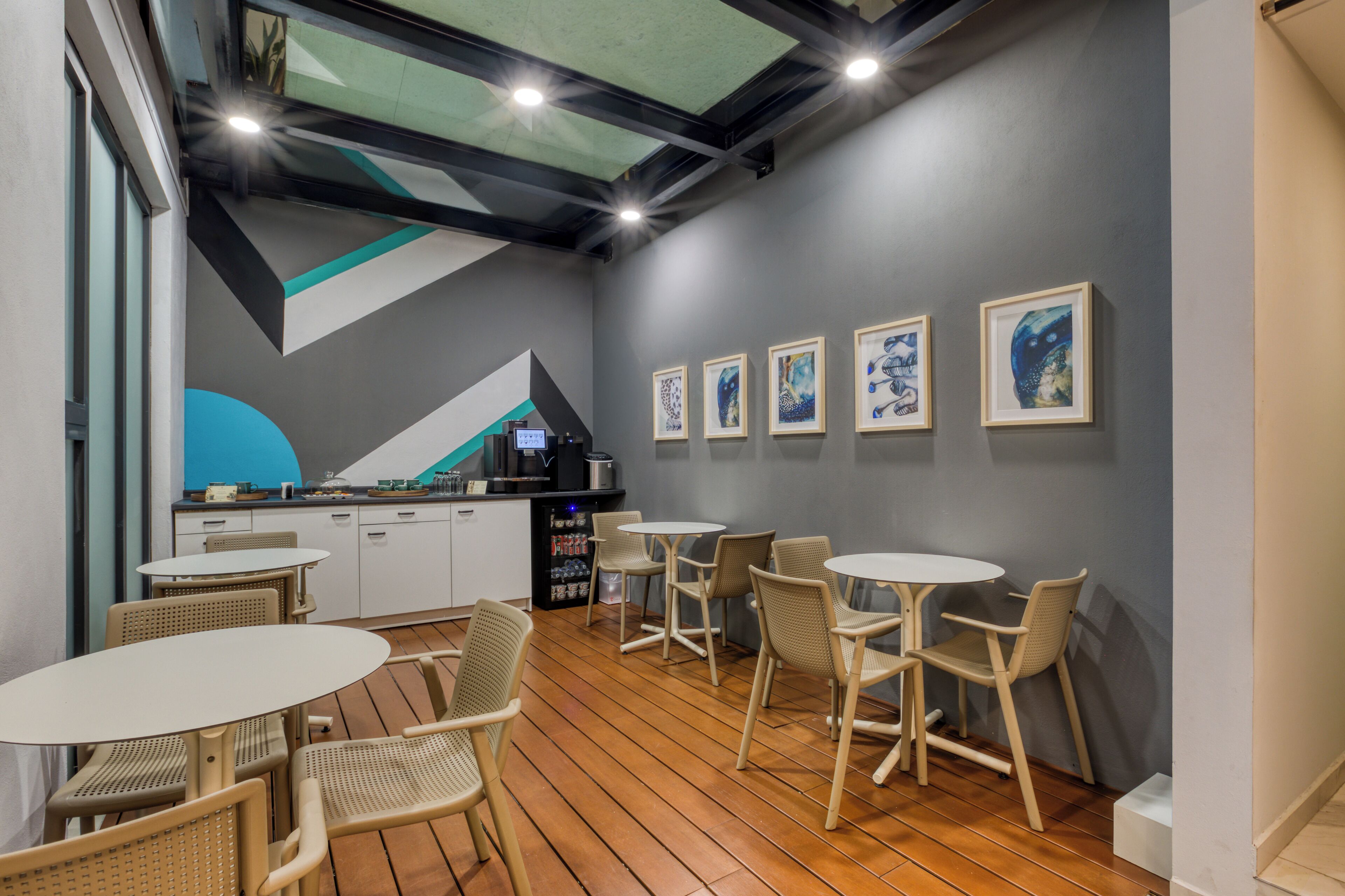 Ein modernes Interieur mit Küchenzeile, Esstischen und Stühlen sowie Kunstwerken an den Wänden.