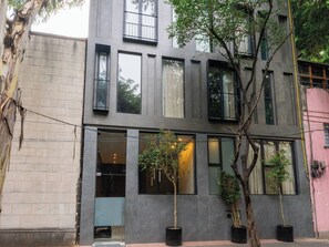 Un edificio moderno con amplios ventanales, entrada visible y plantas en macetas.