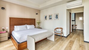 A modern bedroom with a large bed, a bedside table with a vase of flowers, and a chair. - Casa Tokio (Mexico City)