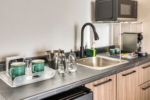 A kitchen with a stainless steel sink, a microwave, and a dish drying rack. - Casa Tokio (Mexico City)