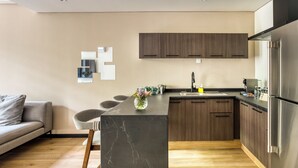 A modern kitchen with a central island, wooden cabinets, and a stainless steel refrigerator. - Casa Tokio (Mexico City)