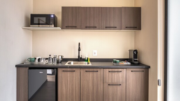 A compact kitchen with a built-in microwave, a sink, and a small refrigerator. - Casa Tokio (Mexico City)