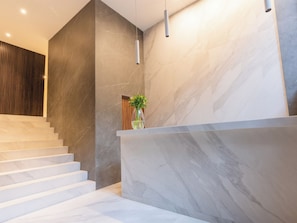A modern staircase with marble walls and a wooden panel on the left.