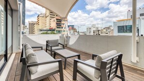 A rooftop terrace with a seating area, including a table and chairs, overlooking a cityscape with various buildings. - Casa Tokio (Mexico City)