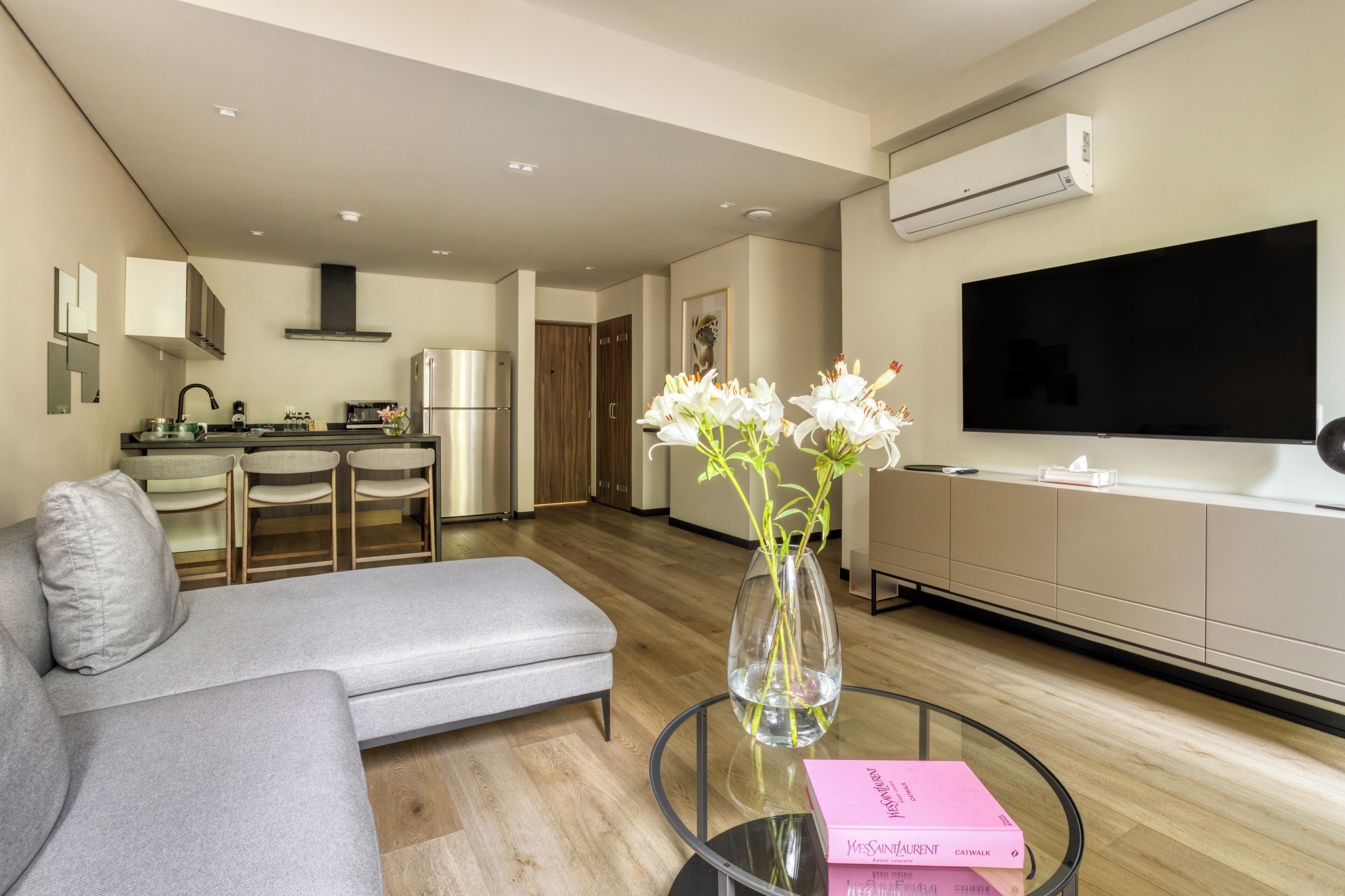 A modern living room with a grey sofa, a glass coffee table, and a vase with flowers.