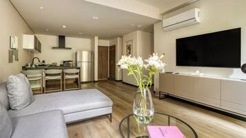 A modern living room with a grey sofa, a glass coffee table, and a vase with flowers.