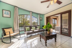 Ein Wohnzimmer mit einer Couch, einem Sessel, einem Couchtisch und einem Deckenventilator.