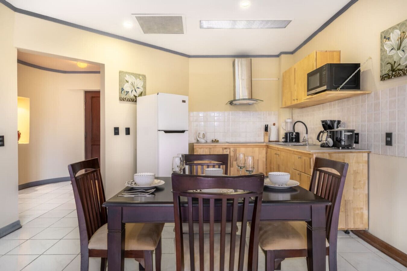Uma cozinha moderna com uma mesa de jantar, cadeiras, micro-ondas e geladeira.